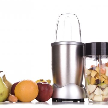 Small blender with fruit around it